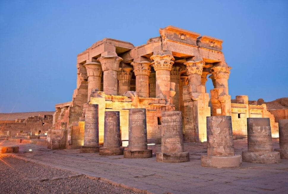 Temple of Kom Ombo in Egypt illuminated at dusk, showcasing ancient stone columns with detailed carvings.