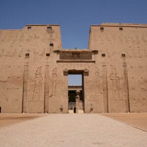 Temple of Edfu in Egypt with massive sandstone walls carved with ancient hieroglyphs and pharaonic reliefs.