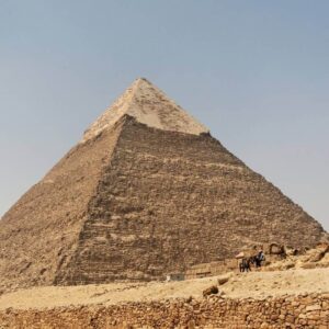 Pyramid of Chephren in Giza, Egypt, with limestone casing at the top and desert landscape below.