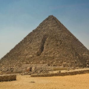 Pyramid of Menkaure in Giza, Egypt, with weathered stone blocks and a visible entrance on its lower side.
