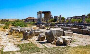 Ruins of Miletus Archaeological Site near Didim, Turkey, with scattered stone columns and ancient structures under a clear blue sky.