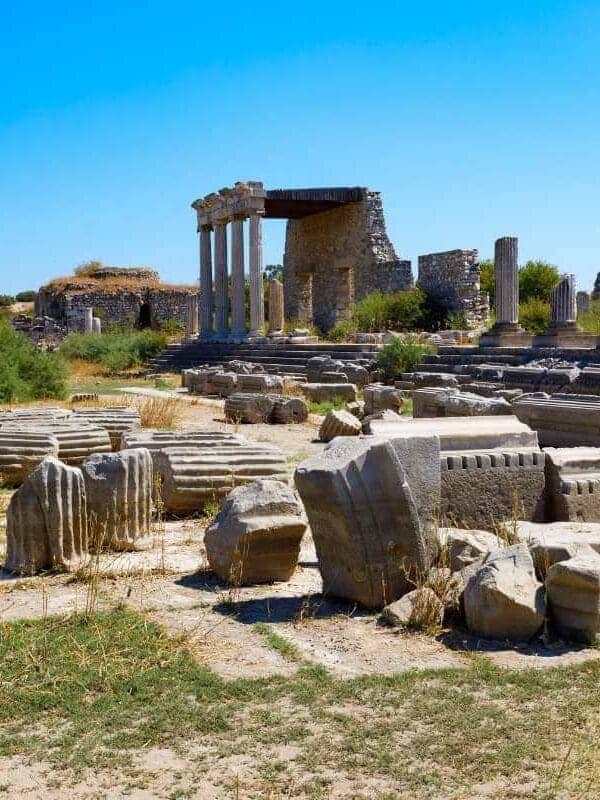 Ruins of Miletus Archaeological Site near Didim, Turkey, with scattered stone columns and ancient structures under a clear blue sky.