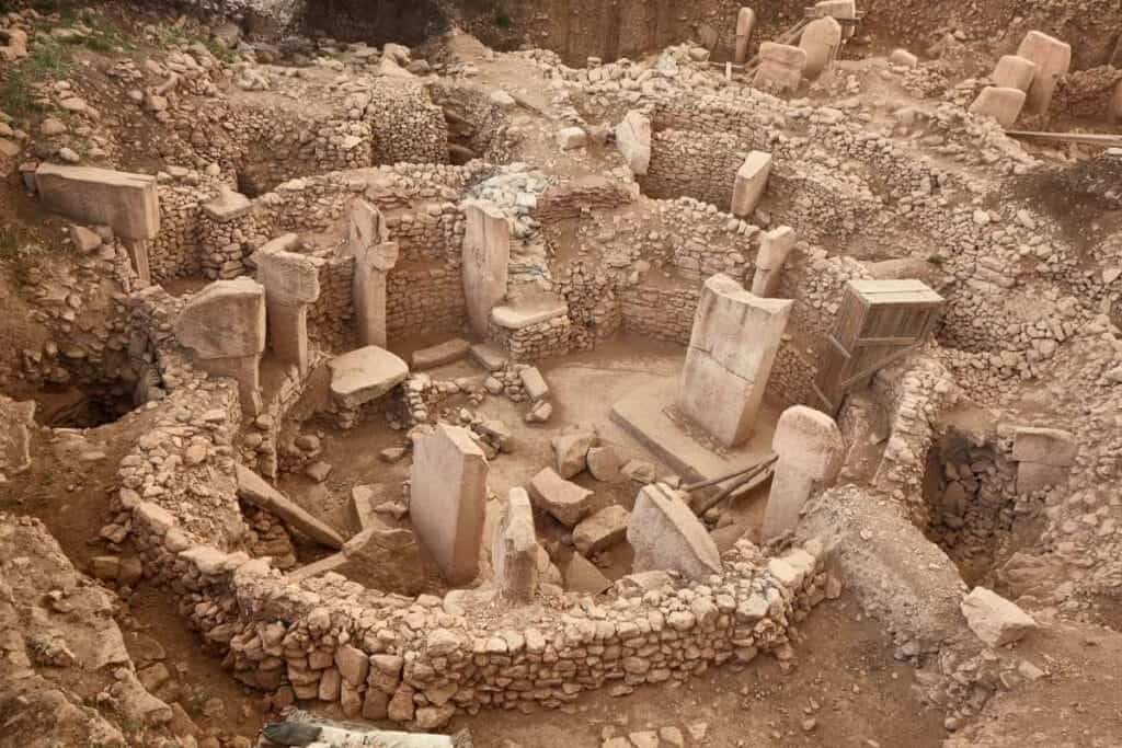 Ancient stone circle ruins of Göbekli Tepe with tall T-shaped pillars and stone walls in southeastern Turkey.