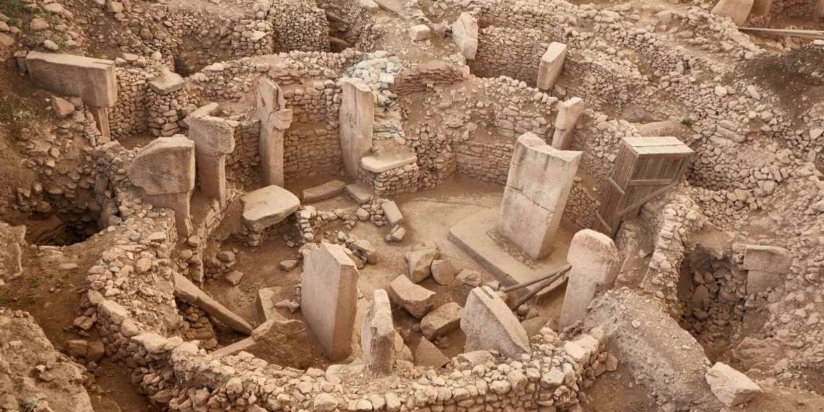 Ancient stone circle ruins of Göbekli Tepe with tall T-shaped pillars and stone walls in southeastern Turkey.