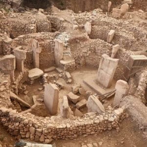 Ancient stone circle ruins of Göbekli Tepe with tall T-shaped pillars and stone walls in southeastern Turkey.