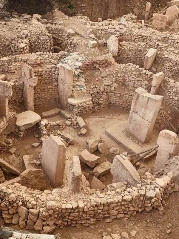 Ancient stone circle ruins of Göbekli Tepe with tall T-shaped pillars and stone walls in southeastern Turkey.