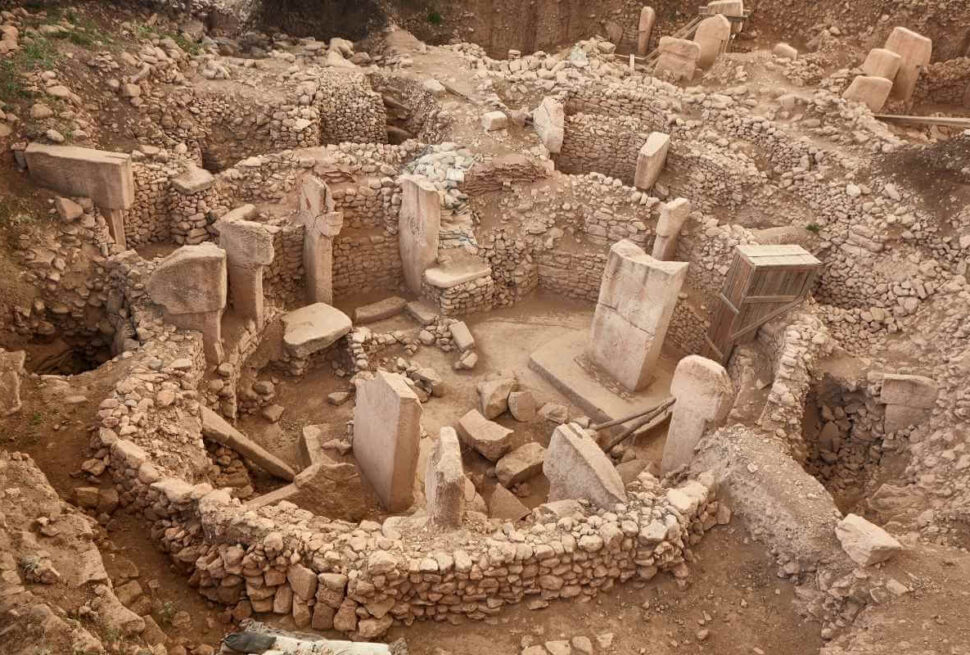 Ancient stone circle ruins of Göbekli Tepe with tall T-shaped pillars and stone walls in southeastern Turkey.