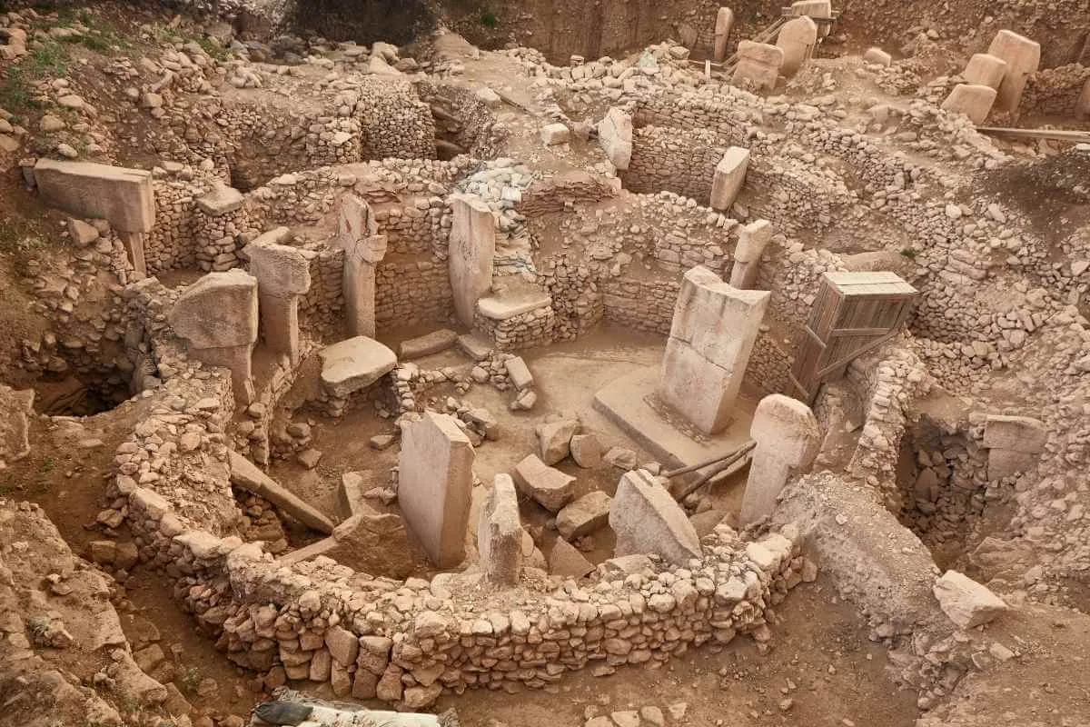 Ancient stone circle ruins of Göbekli Tepe with tall T-shaped pillars and stone walls in southeastern Turkey.