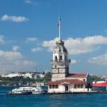 8-Day Istanbul, Cappadocia & Antalya Tour - Cappadocia, Istanbul, Antalya, Turkey Maiden’s Tower on the Bosphorus with Turkish flag, boats nearby, and Istanbul skyline in the background.