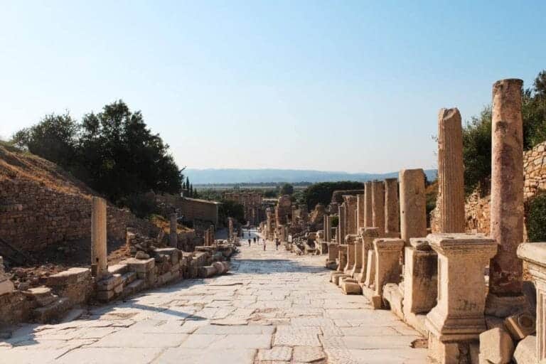 Ancient marble street lined with columns at Ephesus ruins in Selcuk, Turkey, under clear blue sky.