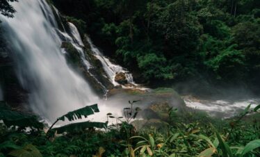 Wachiratharn Waterfall cascading through rocks in a lush jungle near Chiang Mai, Thailand, surrounded by vibrant greenery.
