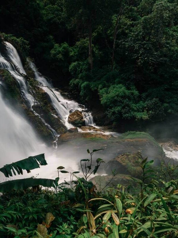 Wachiratharn Waterfall cascading through rocks in a lush jungle near Chiang Mai, Thailand, surrounded by vibrant greenery.
