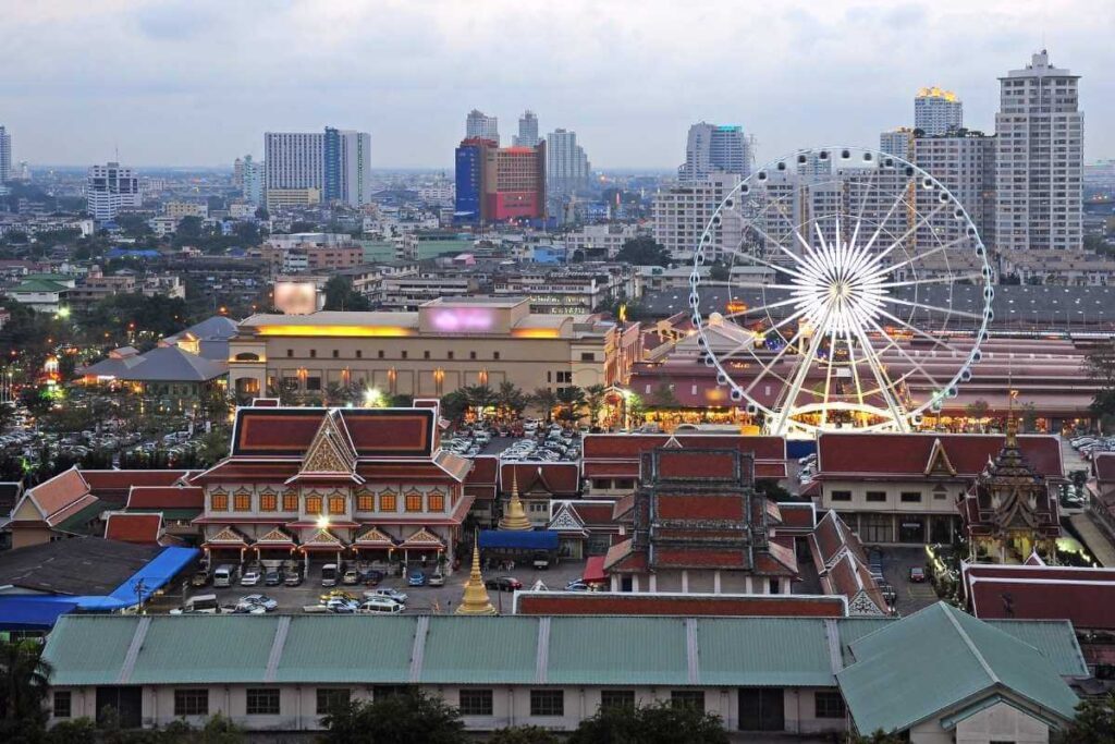 Asiatique The Riverfront in Bangkok with illuminated Ferris wheel, lively market, and modern city skyline in the background.