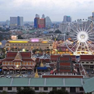 Asiatique The Riverfront in Bangkok with illuminated Ferris wheel, lively market, and modern city skyline in the background.