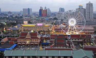 Asiatique The Riverfront in Bangkok with illuminated Ferris wheel, lively market, and modern city skyline in the background.
