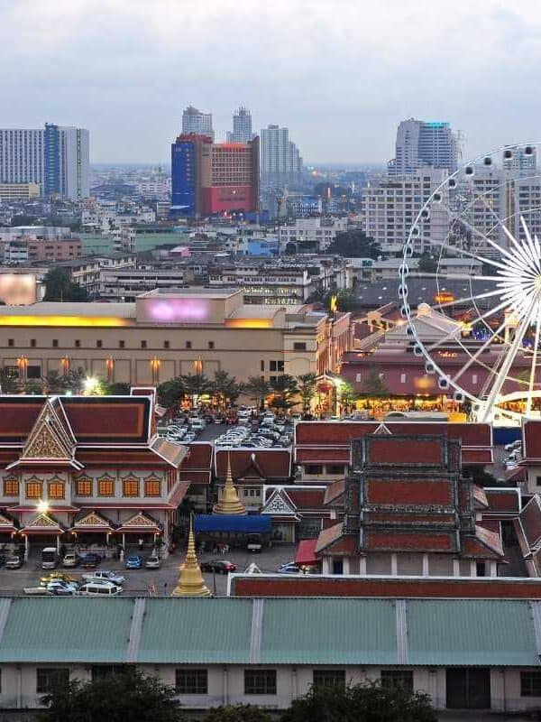 Asiatique The Riverfront in Bangkok with illuminated Ferris wheel, lively market, and modern city skyline in the background.