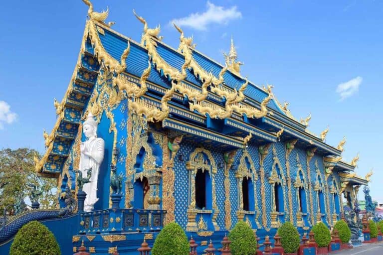 Wat Rong Suea Ten Blue Temple in Chiang Rai with golden carvings, vivid blue walls, and ornate Buddhist architecture.