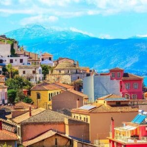 Colorful houses of Nafplio, Greece with terracotta roofs overlooking the sea and mountains under a bright blue sky.