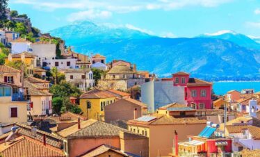 Colorful houses of Nafplio, Greece with terracotta roofs overlooking the sea and mountains under a bright blue sky.