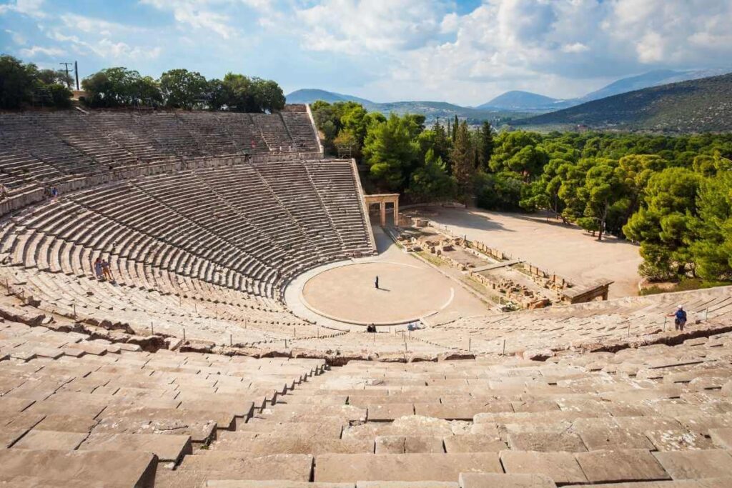Panoramic view of the Ancient Theatre of Epidaurus with stone seating and scenic mountain backdrop in Greece.