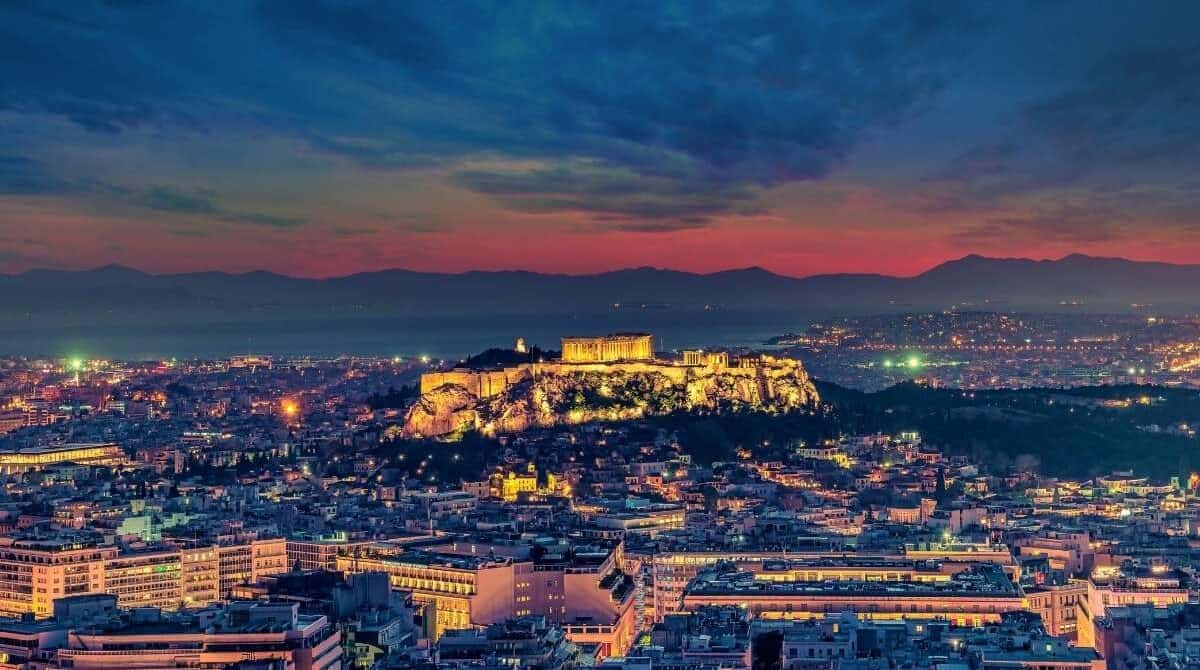 Best Things to Do in Athens – Top Attractions & Activities Guide 1 Illuminated Acropolis of Athens at dusk with city lights and colorful sunset sky in the background.