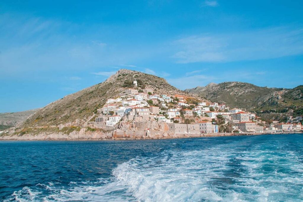 Scenic view of Hydra Island with whitewashed houses on rocky hills overlooking the deep blue Aegean Sea.