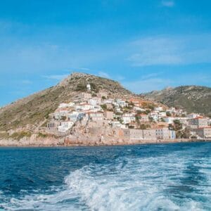 Scenic view of Hydra Island with whitewashed houses on rocky hills overlooking the deep blue Aegean Sea.