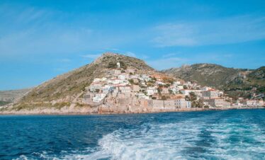 Scenic view of Hydra Island with whitewashed houses on rocky hills overlooking the deep blue Aegean Sea.