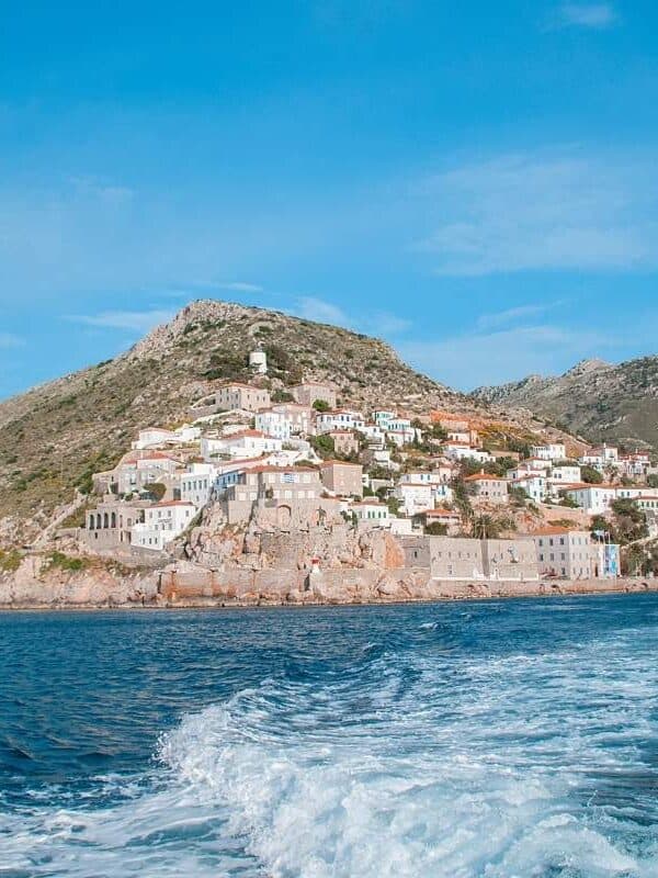 Vista panorámica de la isla de Hydra, con casas encaladas sobre colinas rocosas que dominan el profundo azul del mar Egeo.
