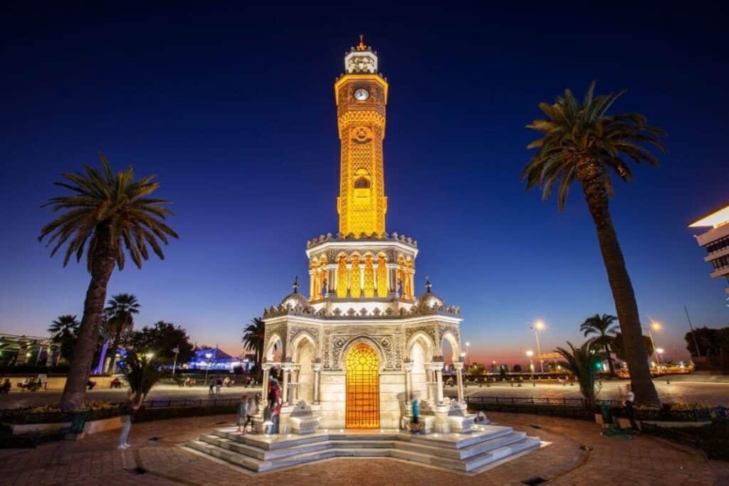 Discover Amazing Turkey Tour Packages for Unforgettable Journeys 3 Illuminated Izmir Clock Tower at dusk with palm trees and deep blue sky in Konak Square, Turkey.