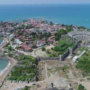 Aerial view of Side Ancient City in Antalya showing the Roman theater, ruins, and coastal old town by the Mediterranean Sea.