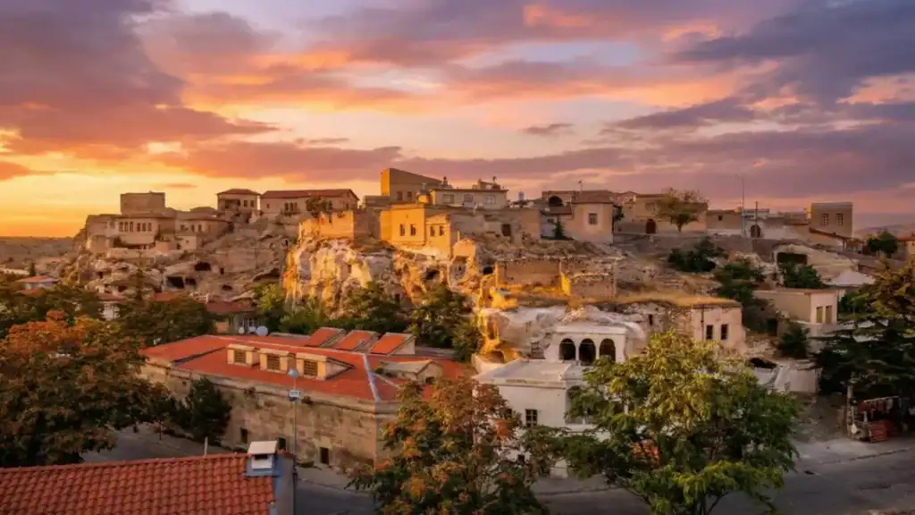 Scenic view of historic stone mansions and cave dwellings in Mustafapaşa (Sinasos) village, Cappadocia, illuminated by the warm light of the sunset.
