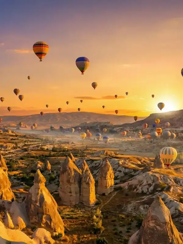 Globos aerostáticos sobrevolando al amanecer las singulares formaciones rocosas y chimeneas de hadas de Capadocia, Turquía. Uno de los momentos culminantes del tour "Lo mejor de Turquía".