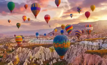 A vibrant hot air balloon ride at sunrise over the unique rock formations and fairy chimneys of Cappadocia, Turkey, a highlight of the 3-Day Cappadocia and Pamukkale Tour.
