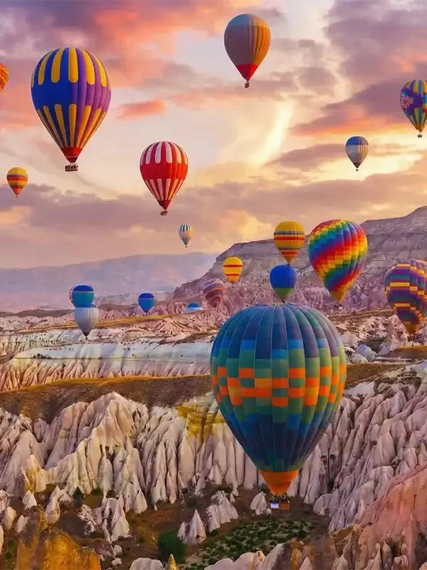 A vibrant hot air balloon ride at sunrise over the unique rock formations and fairy chimneys of Cappadocia, Turkey, a highlight of the 3-Day Cappadocia and Pamukkale Tour.