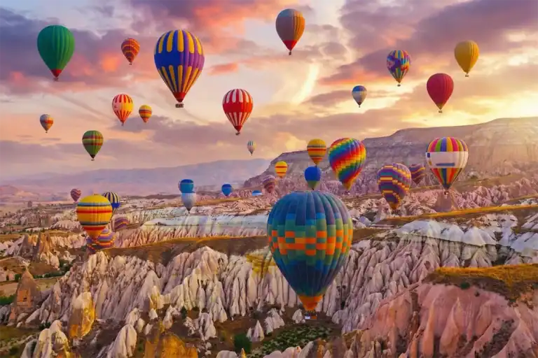 A vibrant hot air balloon ride at sunrise over the unique rock formations and fairy chimneys of Cappadocia, Turkey, a highlight of the 3-Day Cappadocia and Pamukkale Tour.