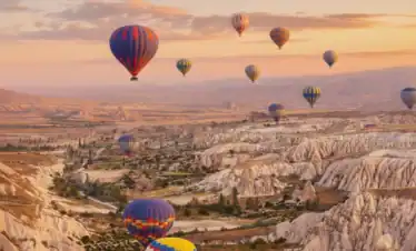 Globos aerostáticos coloridos sobrevolando los valles de Capadocia al amanecer durante una Excursión a Capadocia de 2 Días desde Estambul.