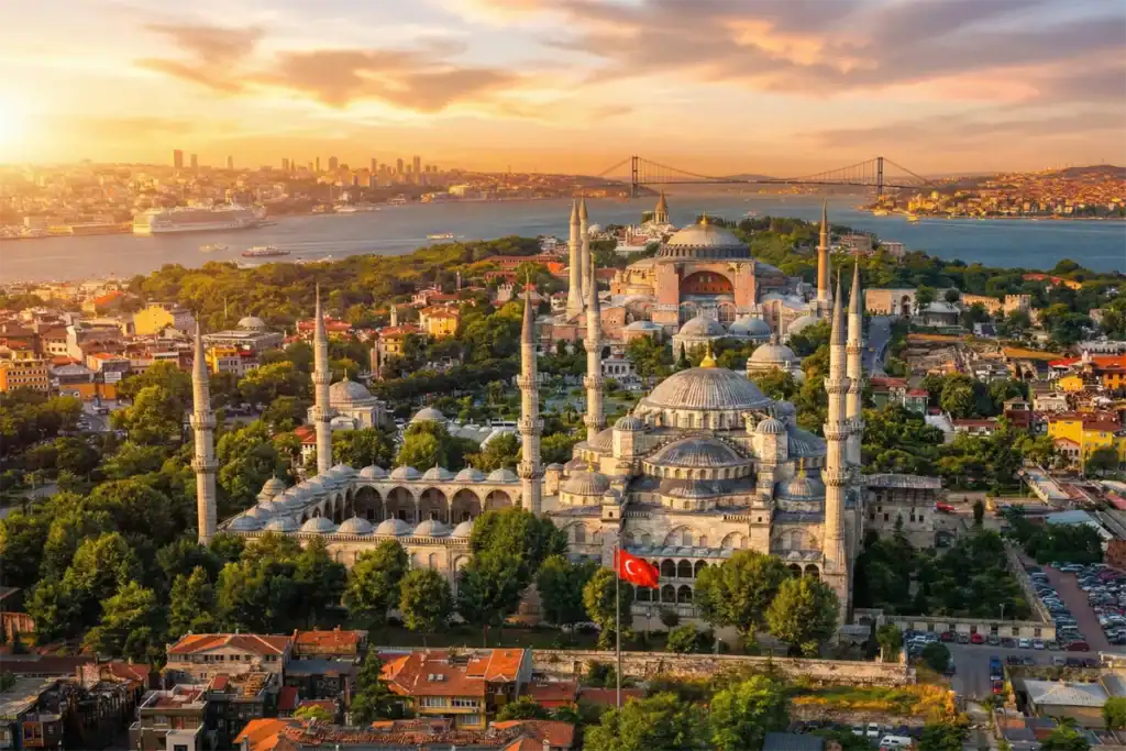 A stunning aerial sunset view overlooking the Hagia Sophia and Blue Mosque on Istanbul's historical peninsula, with the Bosphorus Bridge in the distance. This iconic cityscape is a primary highlight featured in our 7 Days Turkey Tour Packages.