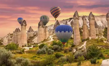 Paisaje espectacular de Capadocia con globos aerostáticos de colores volando sobre las chimeneas de hadas durante el amanecer en Turquía.