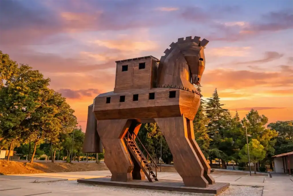 Wooden Trojan Horse statue at the UNESCO World Heritage Site of Troy in Canakkale, Turkey, glowing under a vibrant sunset sky – a top attraction for Turkey travel itineraries.