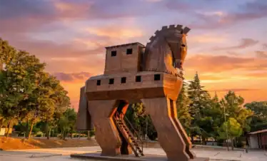 Wooden Trojan Horse statue at the UNESCO World Heritage Site of Troy in Canakkale, Turkey, glowing under a vibrant sunset sky – a top attraction for Turkey travel itineraries.