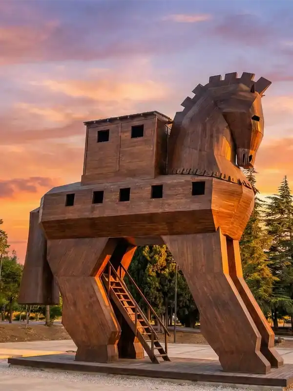 Wooden Trojan Horse statue at the UNESCO World Heritage Site of Troy in Canakkale, Turkey, glowing under a vibrant sunset sky – a top attraction for Turkey travel itineraries.