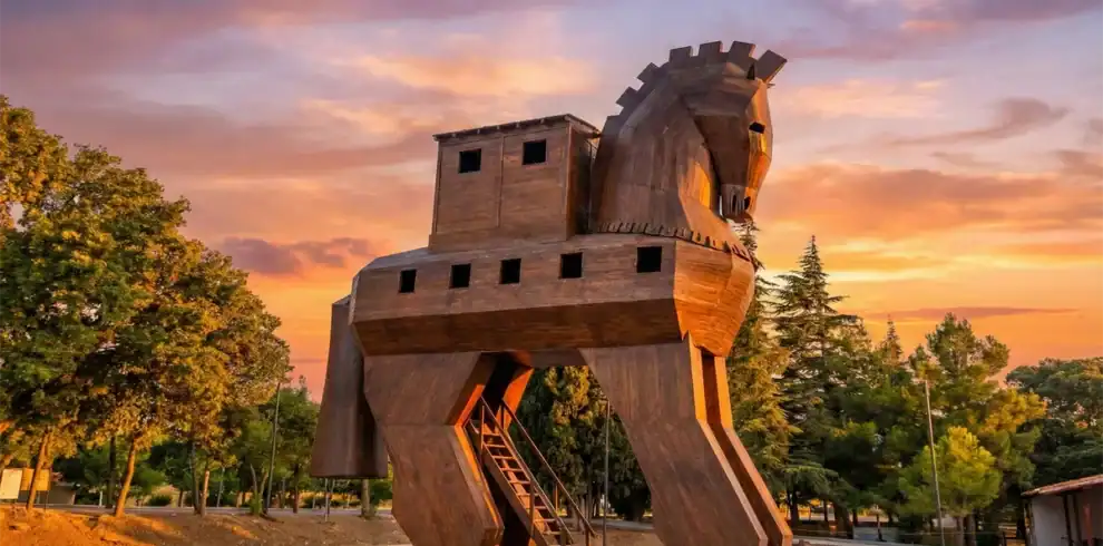 Wooden Trojan Horse statue at the UNESCO World Heritage Site of Troy in Canakkale, Turkey, glowing under a vibrant sunset sky – a top attraction for Turkey travel itineraries.