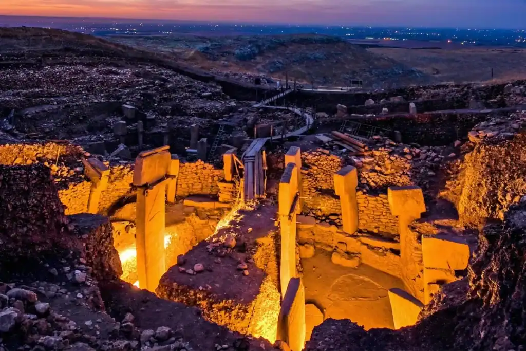 Ultimate Guide to Visiting Göbekli Tepe: History, Tours & Travel Tips 2 Ancient Göbekli Tepe archaeological site illuminated at dusk, showcasing its massive stone pillars a.