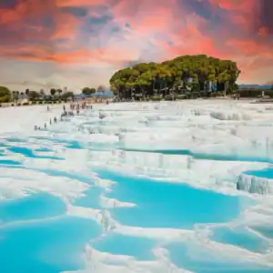 Vista panorámica de las piscinas de travertino blanco de Pamukkale bajo un cielo dramático al atardecer, un destino destacado en el tour de 4 días por Turquía.