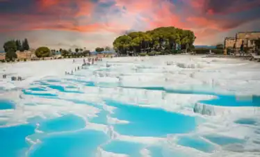 Vista panorámica de las piscinas de travertino blanco de Pamukkale bajo un cielo dramático al atardecer, un destino destacado en el tour de 4 días por Turquía.