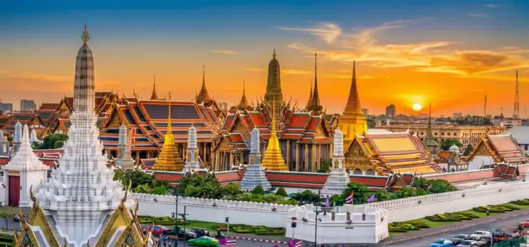 Best Places to Visit in Thailand for First-Timers: Ultimate Guide 1 A breathtaking sunset illuminating the golden spires and intricate tiered rooftops of the Grand Palace and Wat Phra Kaew in Bangkok, a premier destination featured in exclusive Thailand tours by One Nation Travel.