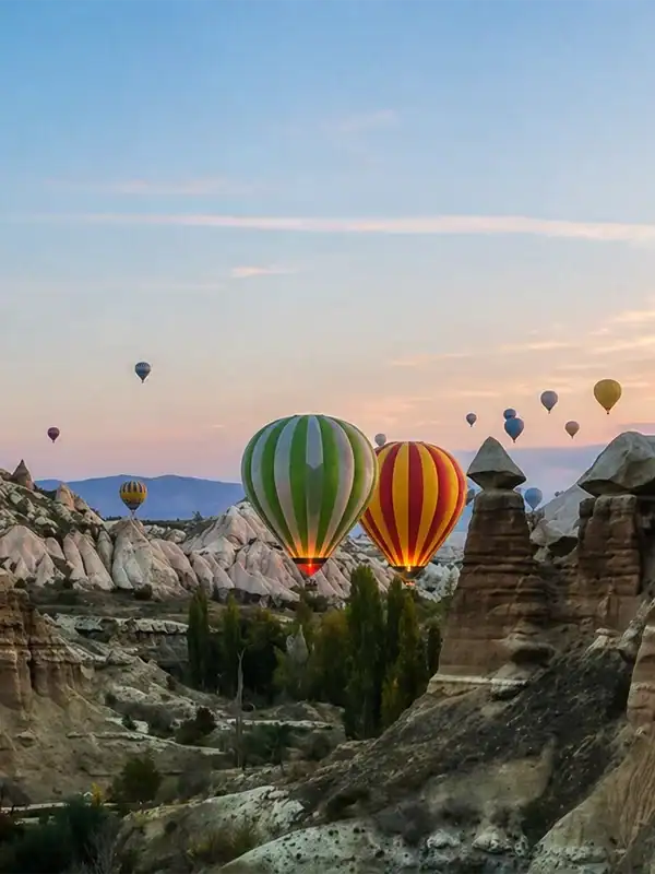 Hot air balloons flying over Cappadocia’s fairy chimneys at sunrise with colorful sky
