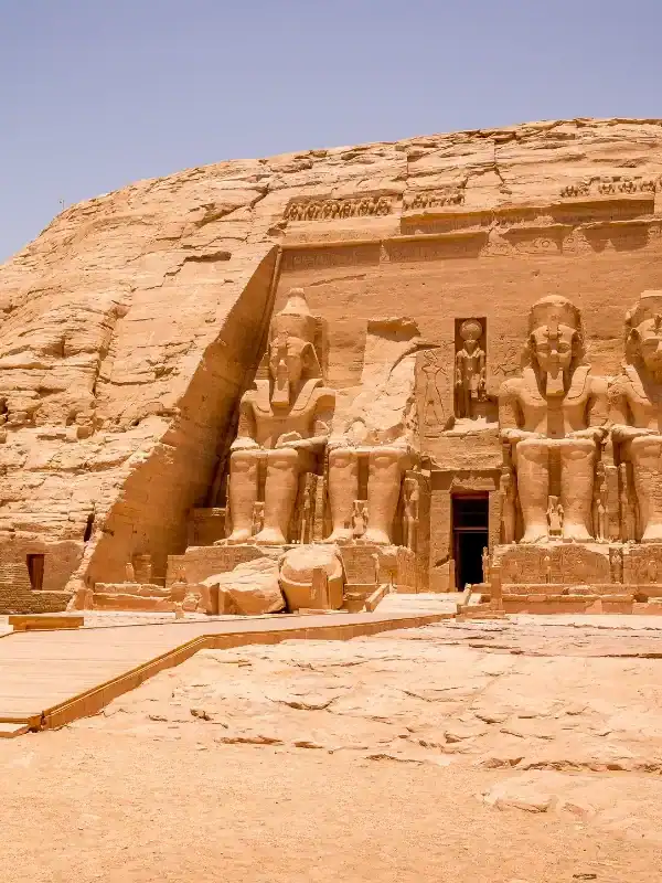 Abu Simbel temple façade with colossal Ramses II statues carved into sandstone cliff under clear desert sky in Egypt