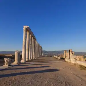 Laodicea colonnaded street in Denizli, Turkey, with ancient stone ruins and mountain views under blue sky